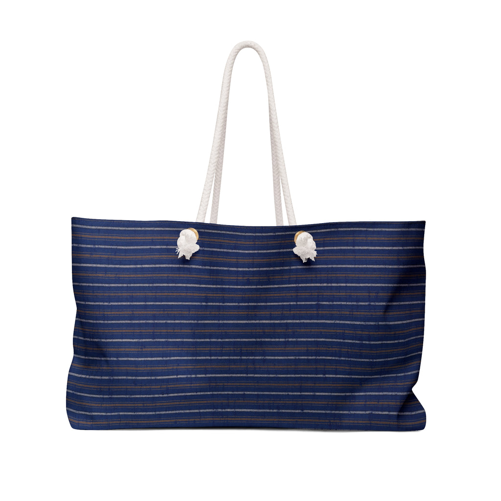 A navy blue tote bag with thin horizontal gold stripes and thick white rope handles, shown against a plain white background.