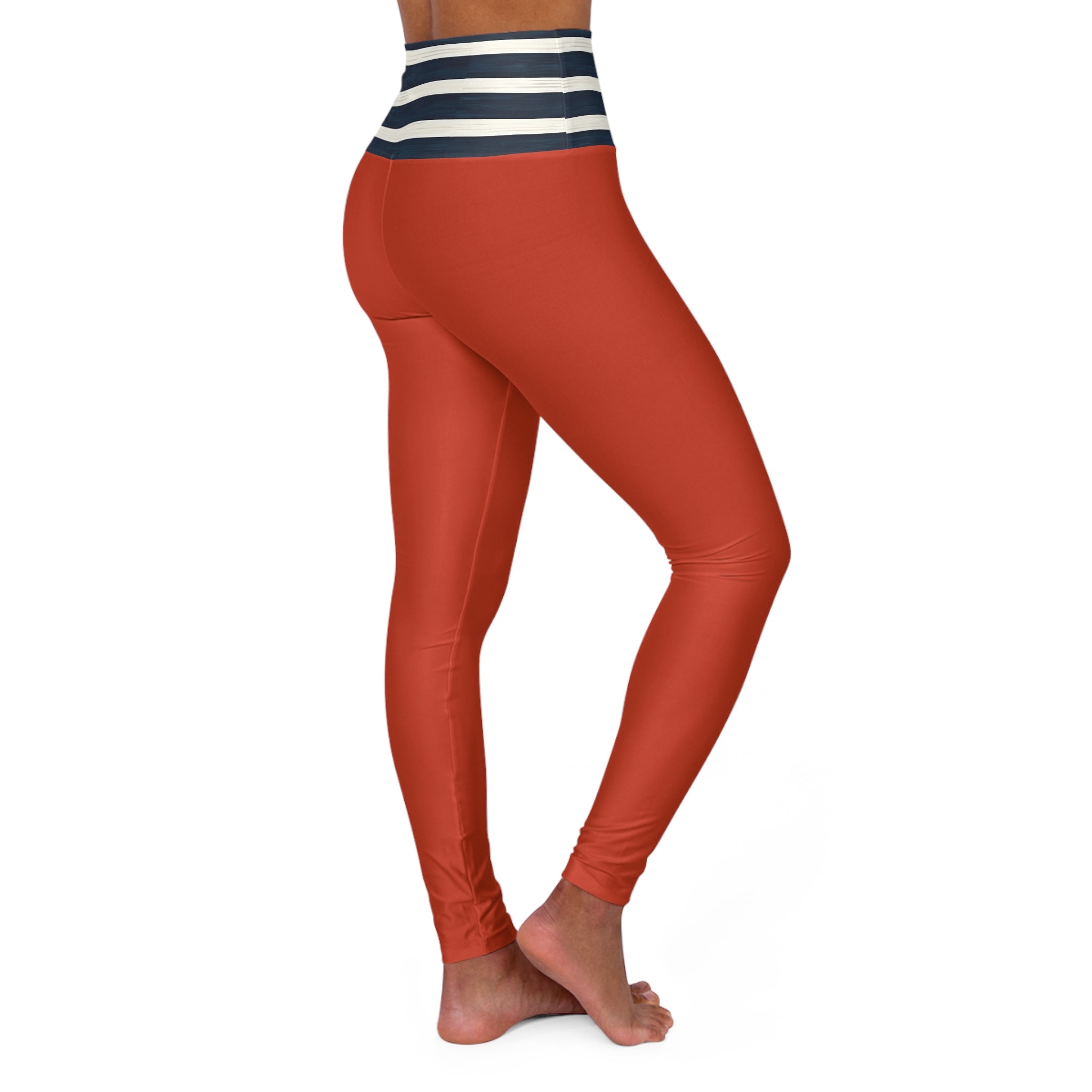 A person modeling high-waisted leggings against a plain white background. The leggings are a warm rust or terracotta color with a striped waistband in navy and white.