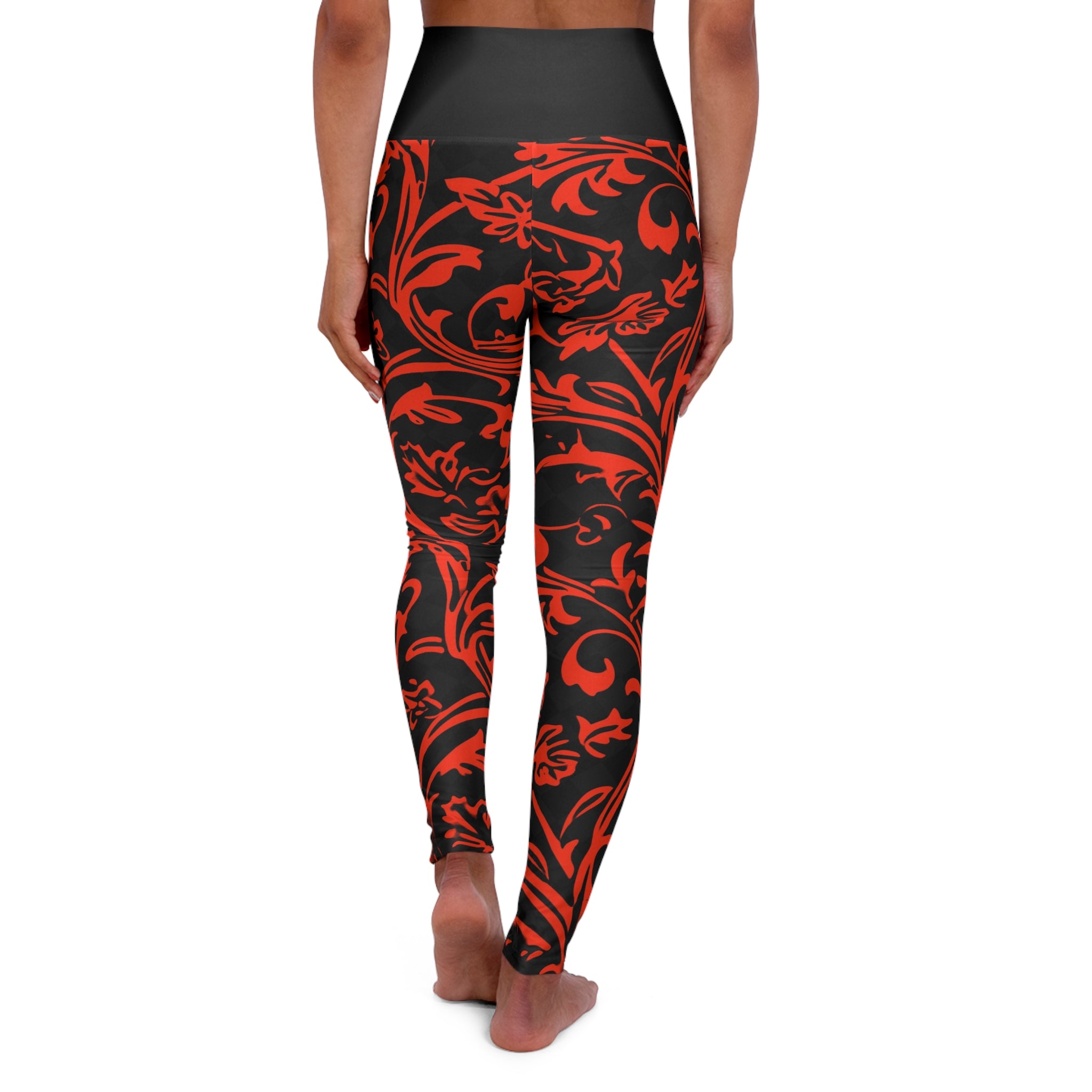 A person shown from the back wearing high-waisted leggings with a black base and a bold red ornamental floral pattern, standing barefoot against a plain white background.
