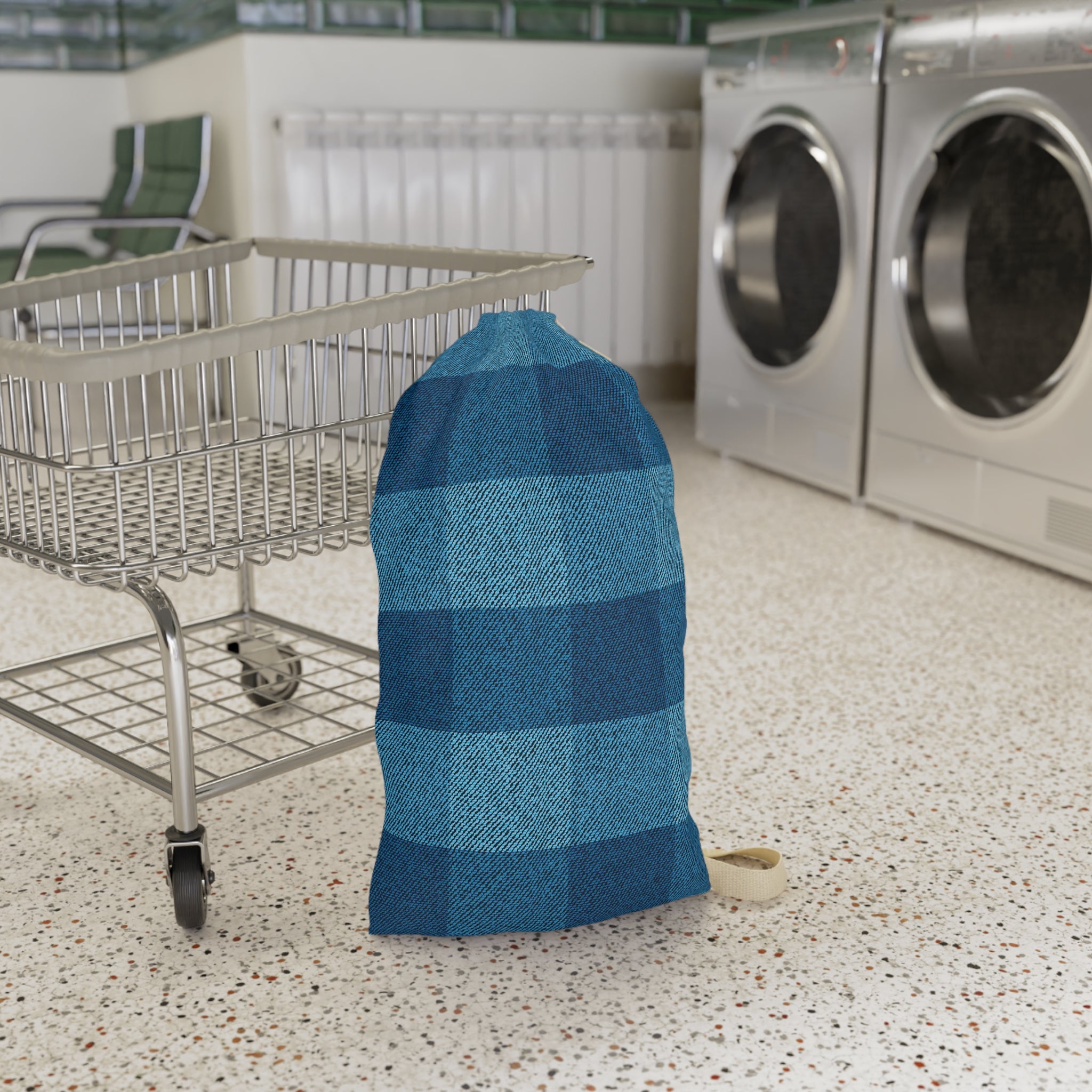 A blue and navy buffalo plaid laundry bag standing on a speckled floor next to a metal shopping cart, with washing machines in the background.