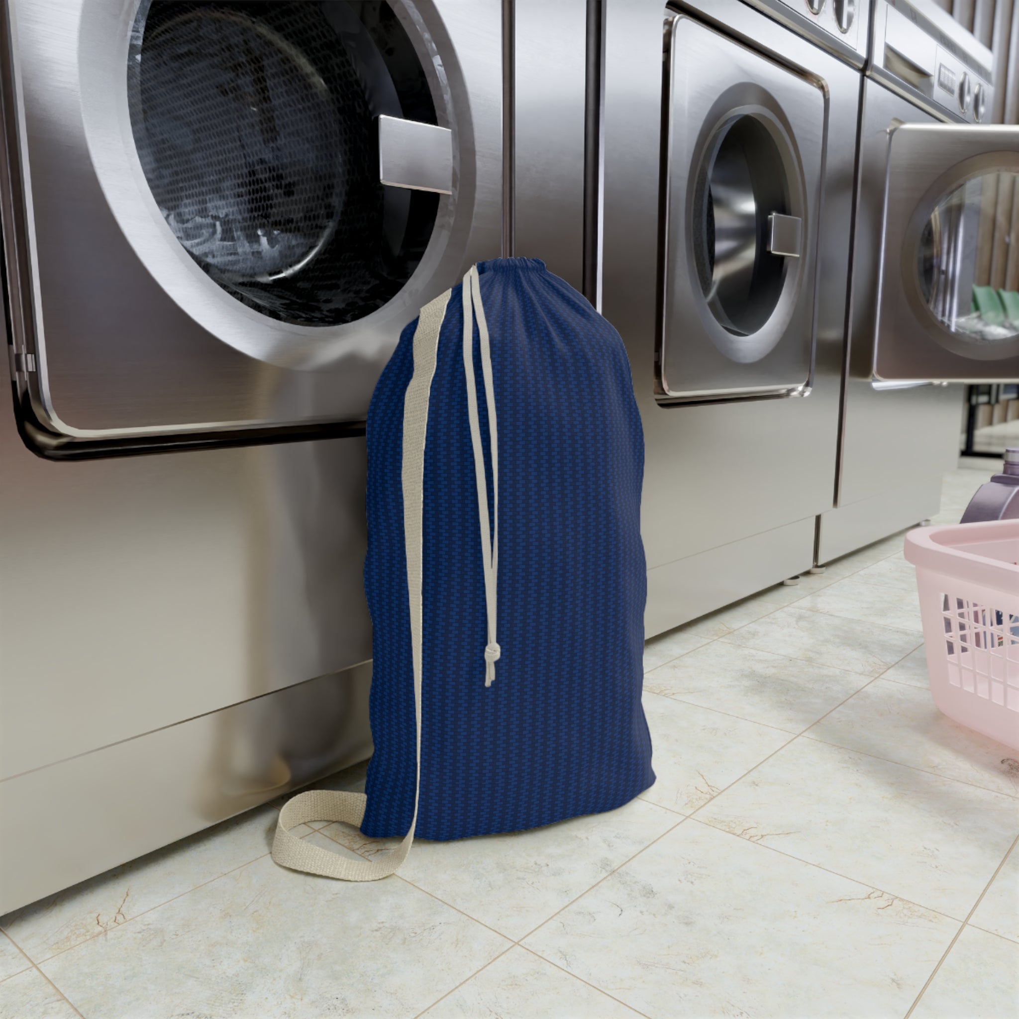 Blue drawstring bag with a logo in front of washing machines in a laundromat.