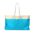 A tote bag with a cream top section and a bright blue lower section featuring vertical stripes, complete with two white rope handles.