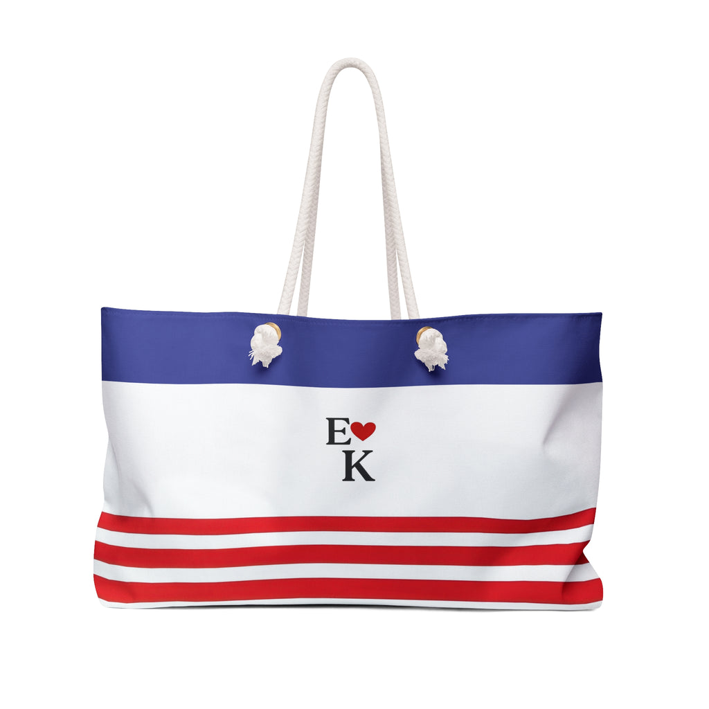 A tote bag with a blue, white, and red horizontal stripe design, featuring a central logo that reads 'E [heart] K' and two white rope handles.
