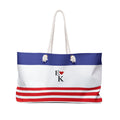 A tote bag with a blue, white, and red horizontal stripe design, featuring a central logo that reads 'E [heart] K' and two white rope handles.