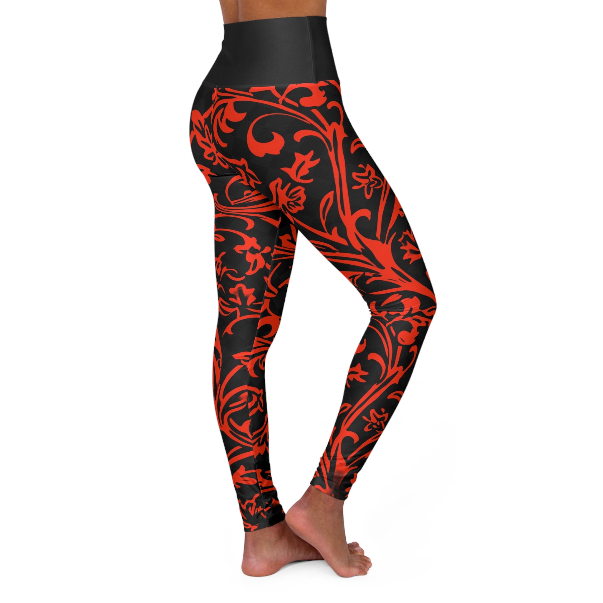 A person modeling high-waisted leggings with a black base and a bold red ornamental floral pattern, shown from the waist down against a plain white background.