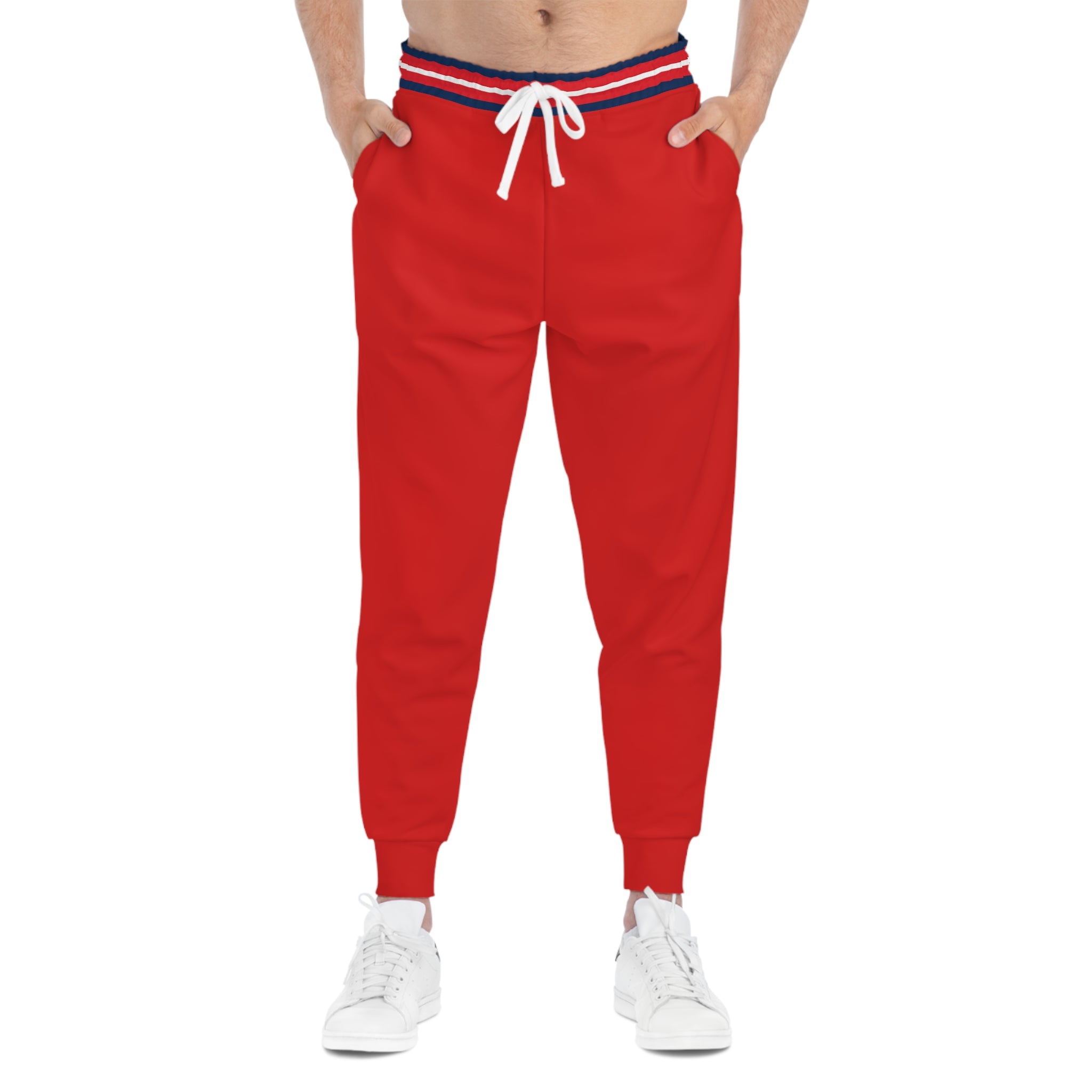 Red jogger sweatpants with a navy and red striped elastic waistband, white drawstring, and side pockets, shown on a model from the waist down wearing white sneakers.