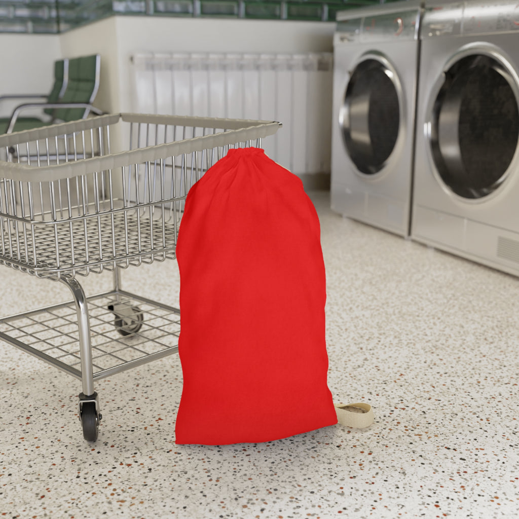 A bright red drawstring laundry bag standing on a speckled floor next to a metal shopping cart, with washing machines in the background.