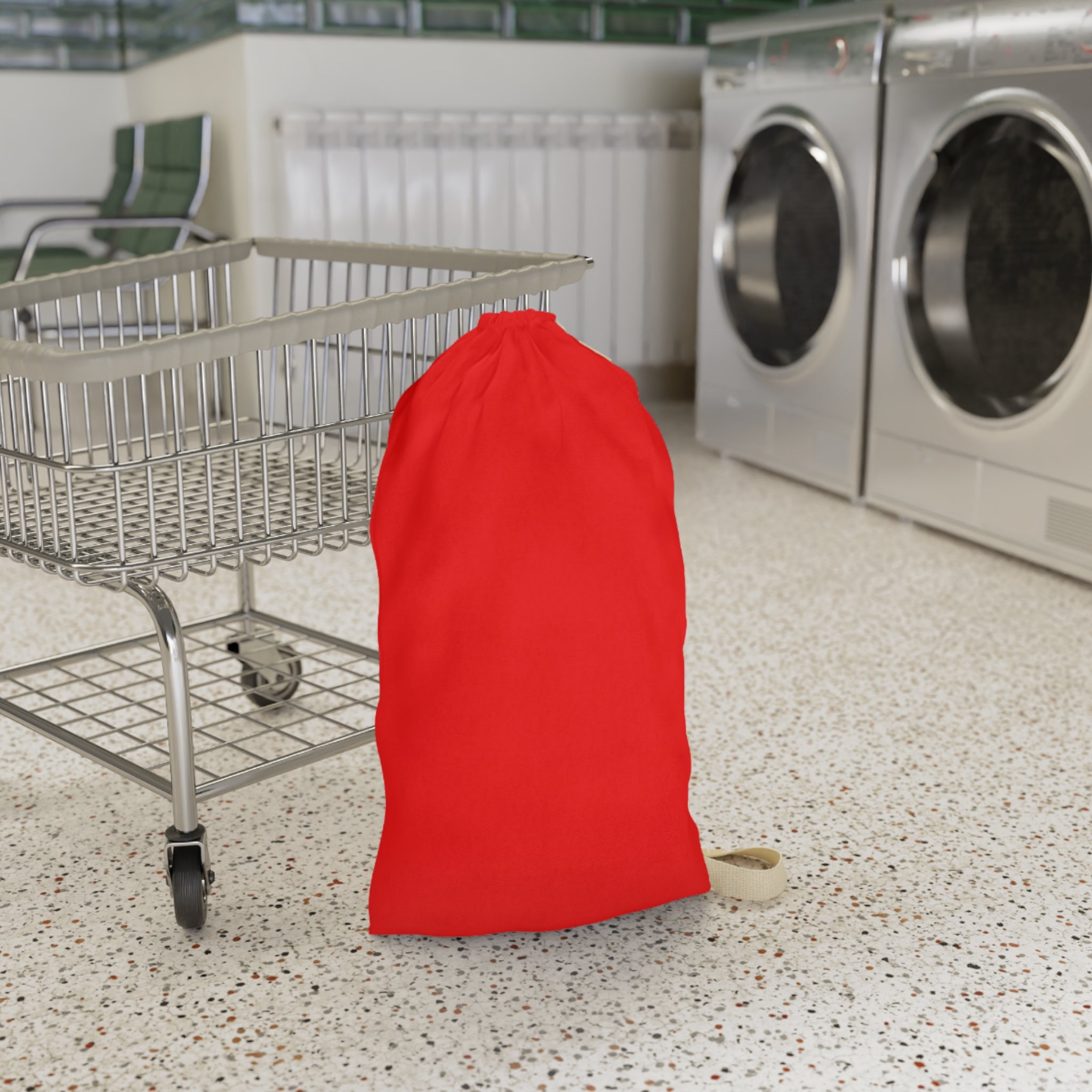 A bright red drawstring laundry bag standing on a speckled floor next to a metal shopping cart, with washing machines in the background.