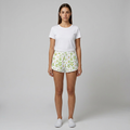 Woman wearing a white t-shirt and floral shorts on a gray background