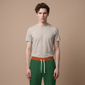 A man modeling a light beige crew-neck t-shirt and green drawstring sweatpants with a textured orange waistband, set against a solid beige studio background.