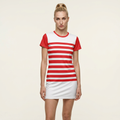 A woman modeling a short-sleeve athletic dress with horizontal red and white stripes on the torso and solid red sleeves, paired with a white skirt, against a light beige studio background.