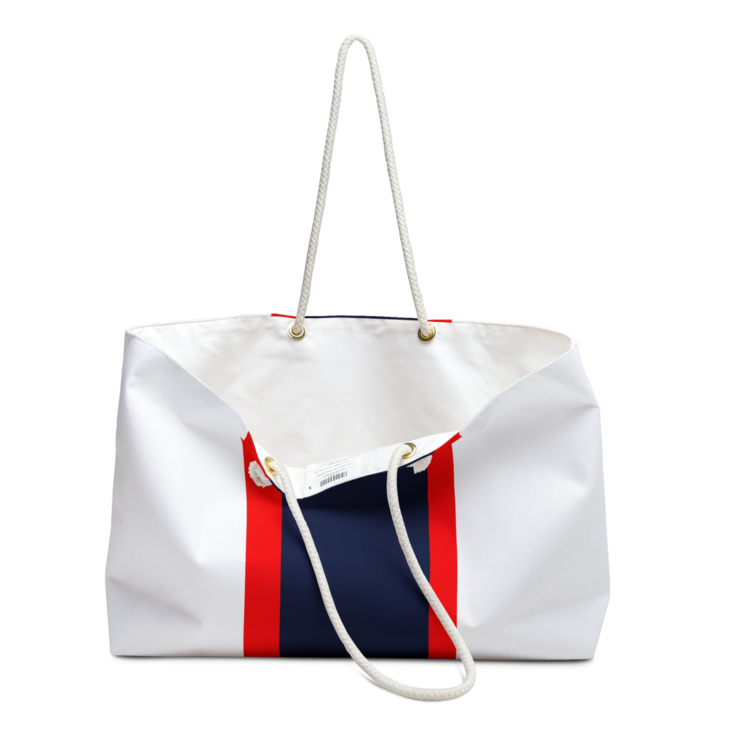 A white canvas tote bag with a navy blue center panel and red side stripes, featuring white rope handles and gold-tone hardware, shown on a plain white background.