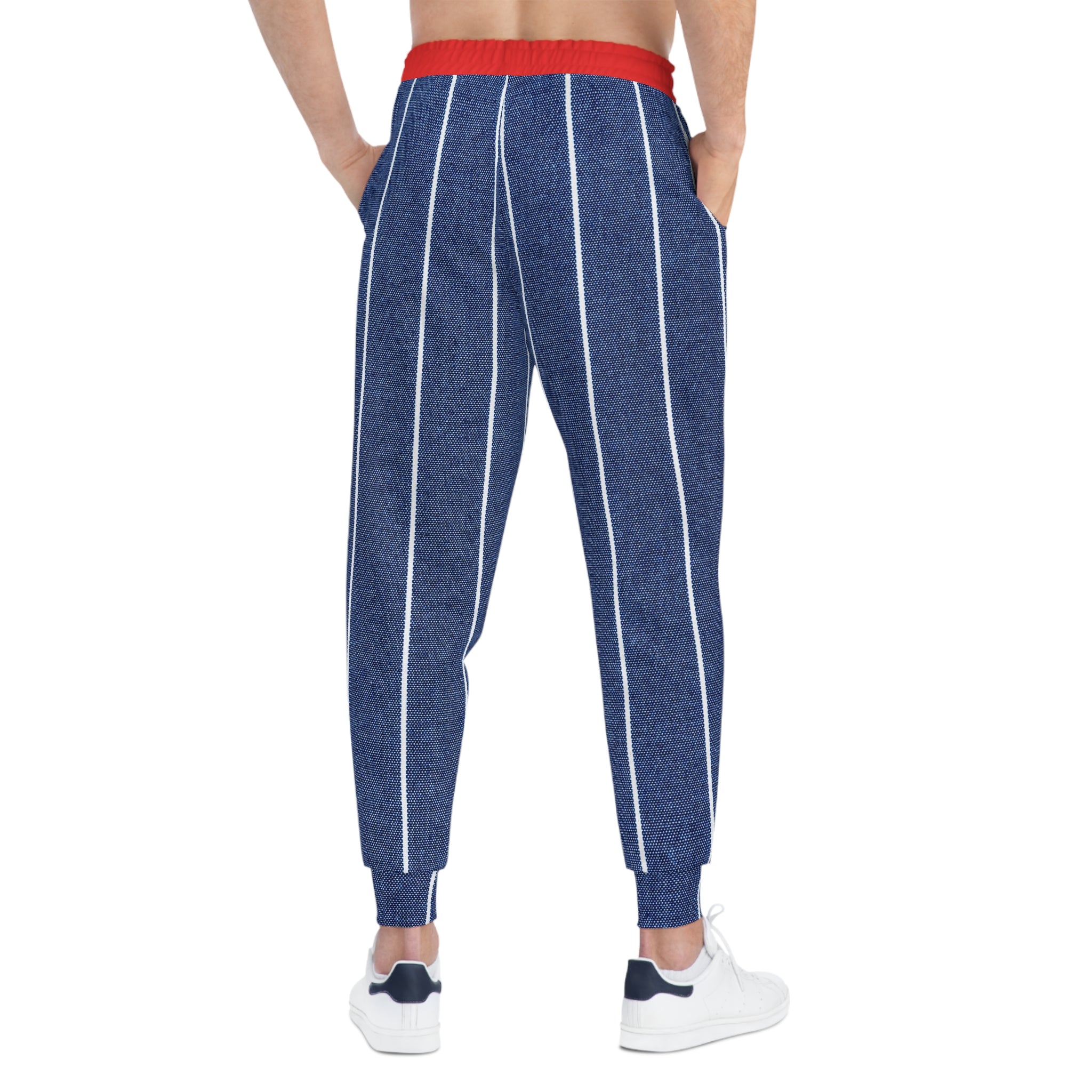 A person shown from the back wearing blue jogger-style pants with white vertical stripes and a red elastic waistband, paired with white sneakers on a plain white background.
