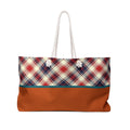 A tote bag with a red, navy, and cream plaid pattern on the upper half and a solid rust-orange lower half, featuring white rope handles.