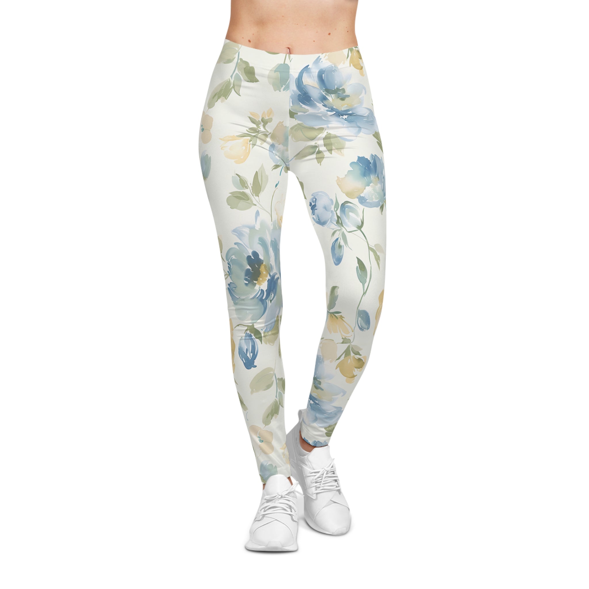 A person wearing high-waisted leggings with a watercolor floral print in blue, green, and beige on an off-white background, paired with white sneakers, shown against a plain white studio background.