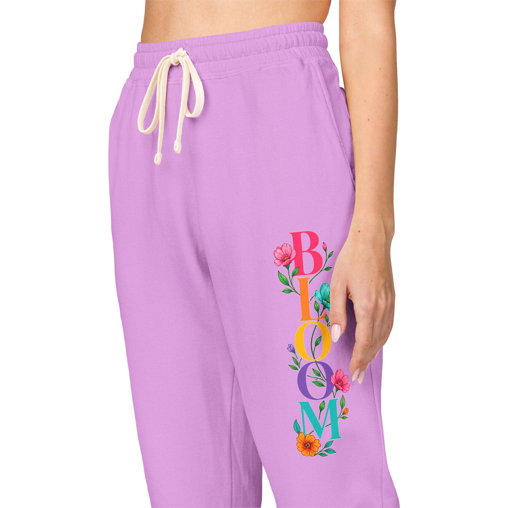 Purple sweatpants with 'BLOOM' and floral design on a white background