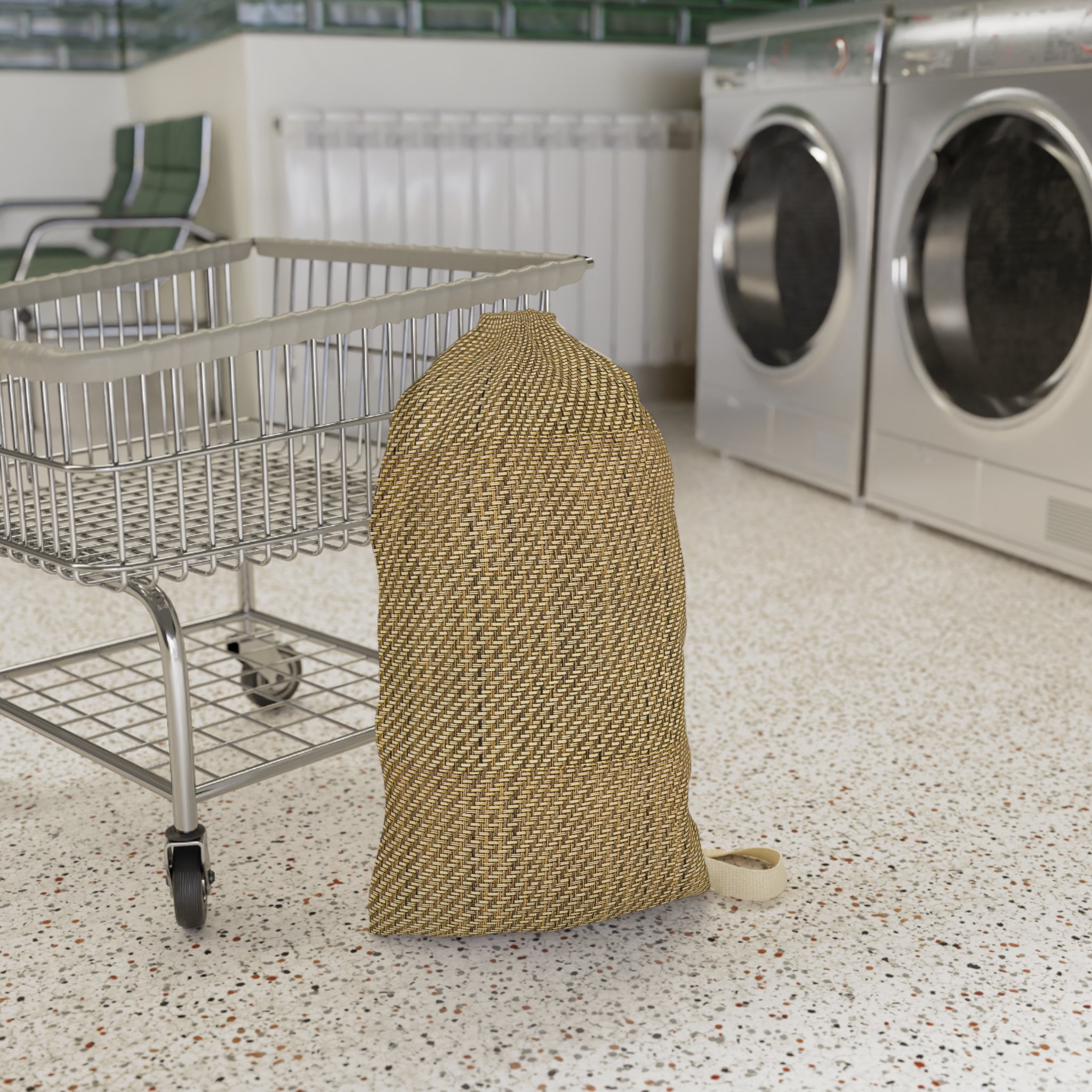 A beige woven mesh laundry bag with a small white drawstring loop, standing on a speckled floor next to a metal shopping cart in a laundry room with washing machines in the background.