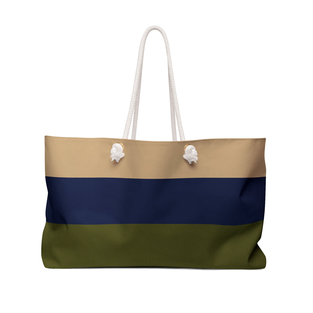 A horizontal-striped tote bag with white rope handles, featuring three color bands: beige on top, navy blue in the middle, and olive green on the bottom, with two white decorative pom-pom accents on the handles.