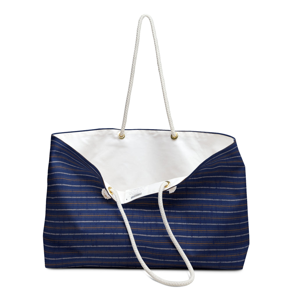 A navy blue canvas tote bag with thin gold stripes, featuring a white rope handle and a white canvas interior, shown against a plain white background.