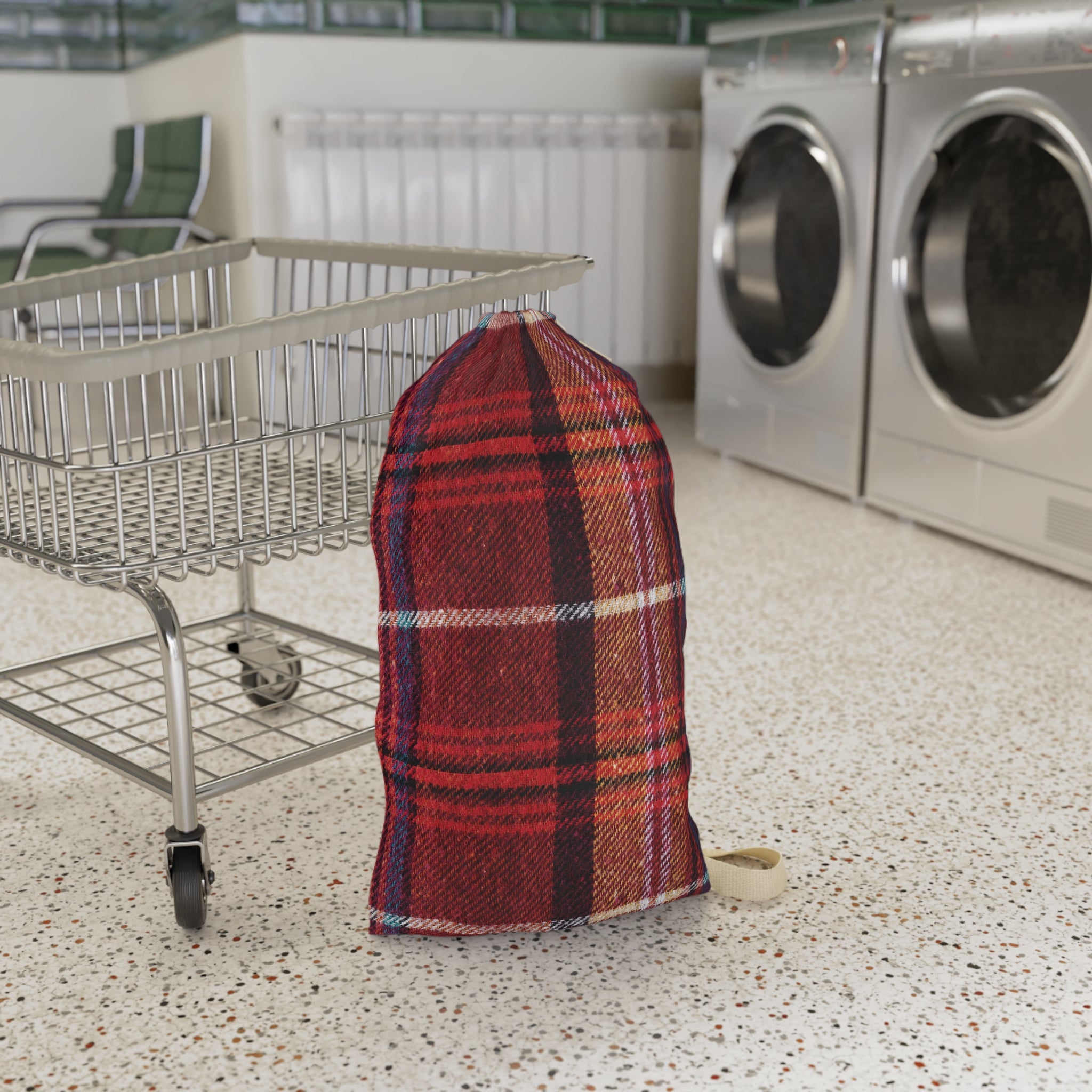 A red and black plaid woven laundry bag standing on a speckled floor next to a metal shopping cart, with washing machines in the background.
