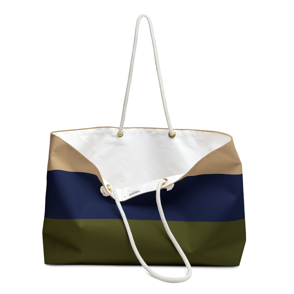 A color-blocked canvas tote bag with white rope handles, featuring horizontal stripes of olive green, navy blue, beige, and white on a plain white background.