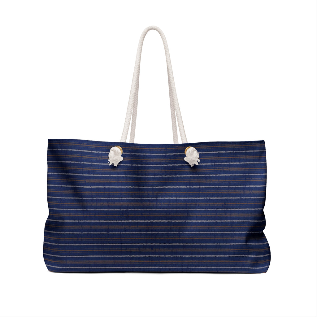 A navy blue tote bag with thin white and gold pinstripes, featuring thick white rope handles and two white decorative shell accents near the top.