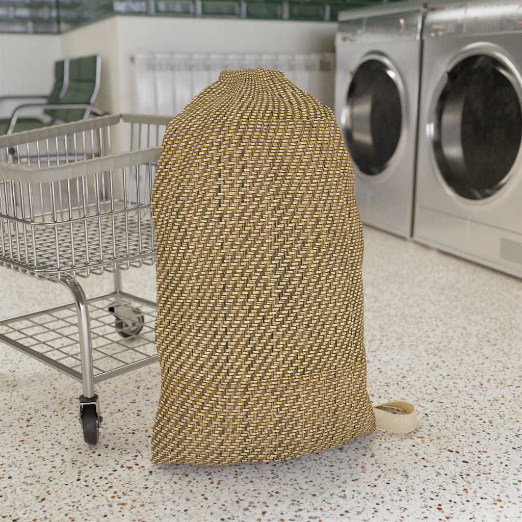 A large woven laundry bag in a tan and brown patterned material, standing on a speckled floor next to a metal shopping cart with a roll of tape on a laundromat floor with washing machines in the background.