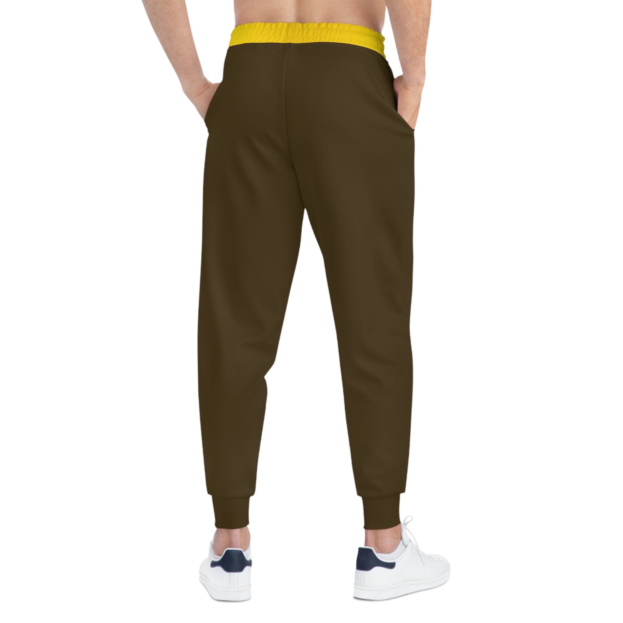 A person shown from the back wearing dark brown jogger-style pants with a bright yellow elastic waistband, paired with white sneakers, on a plain white background.
