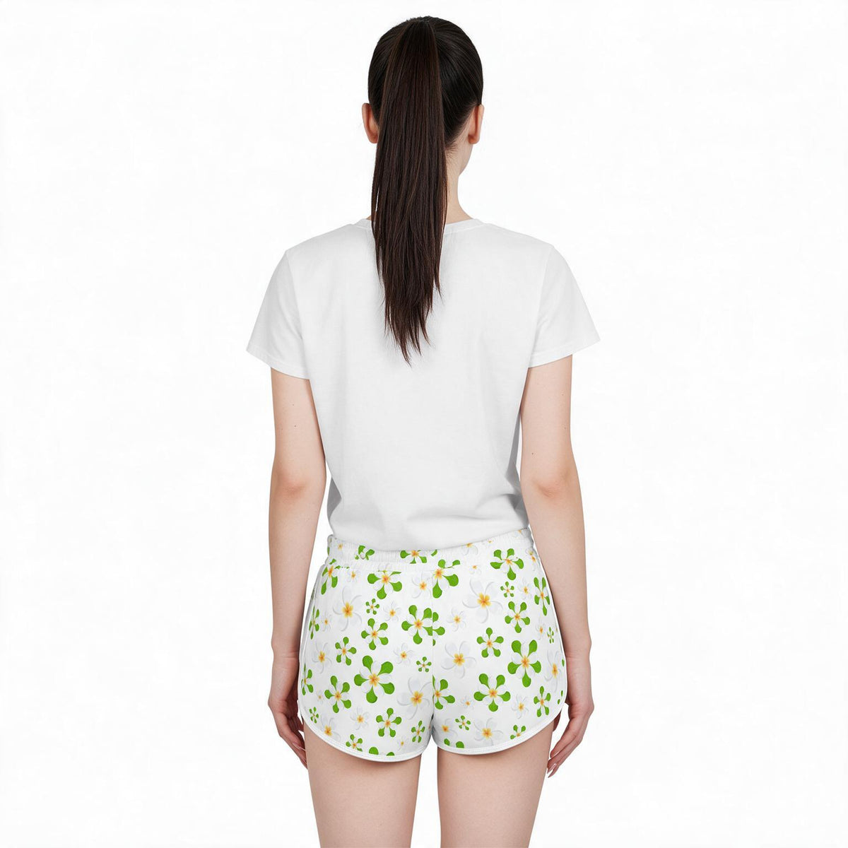 A woman viewed from the back wearing a plain white short-sleeve T-shirt and white shorts with a green and yellow clover pattern, set against a solid white background.