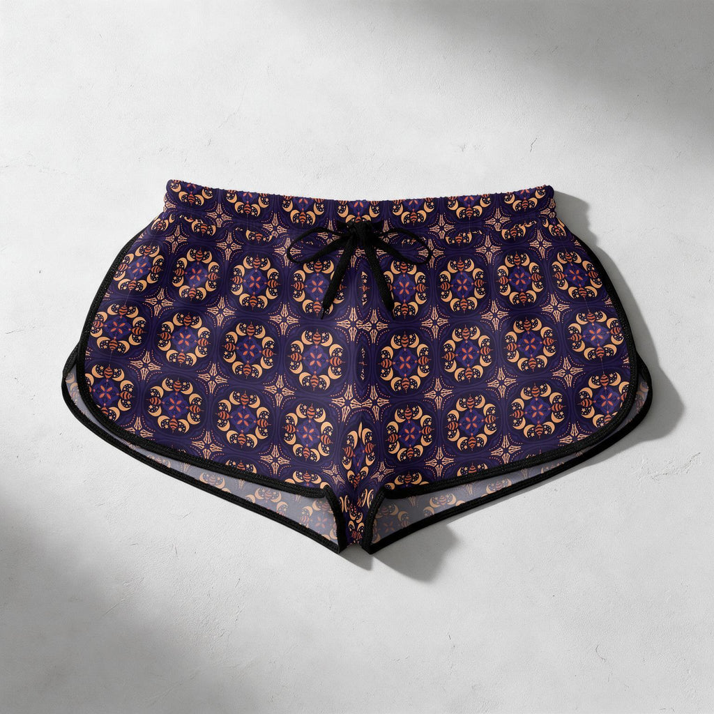 A pair of women's swim trunks featuring a dark purple and gold geometric pattern, with a black drawstring waist and black trim, laid flat on a light gray textured background.