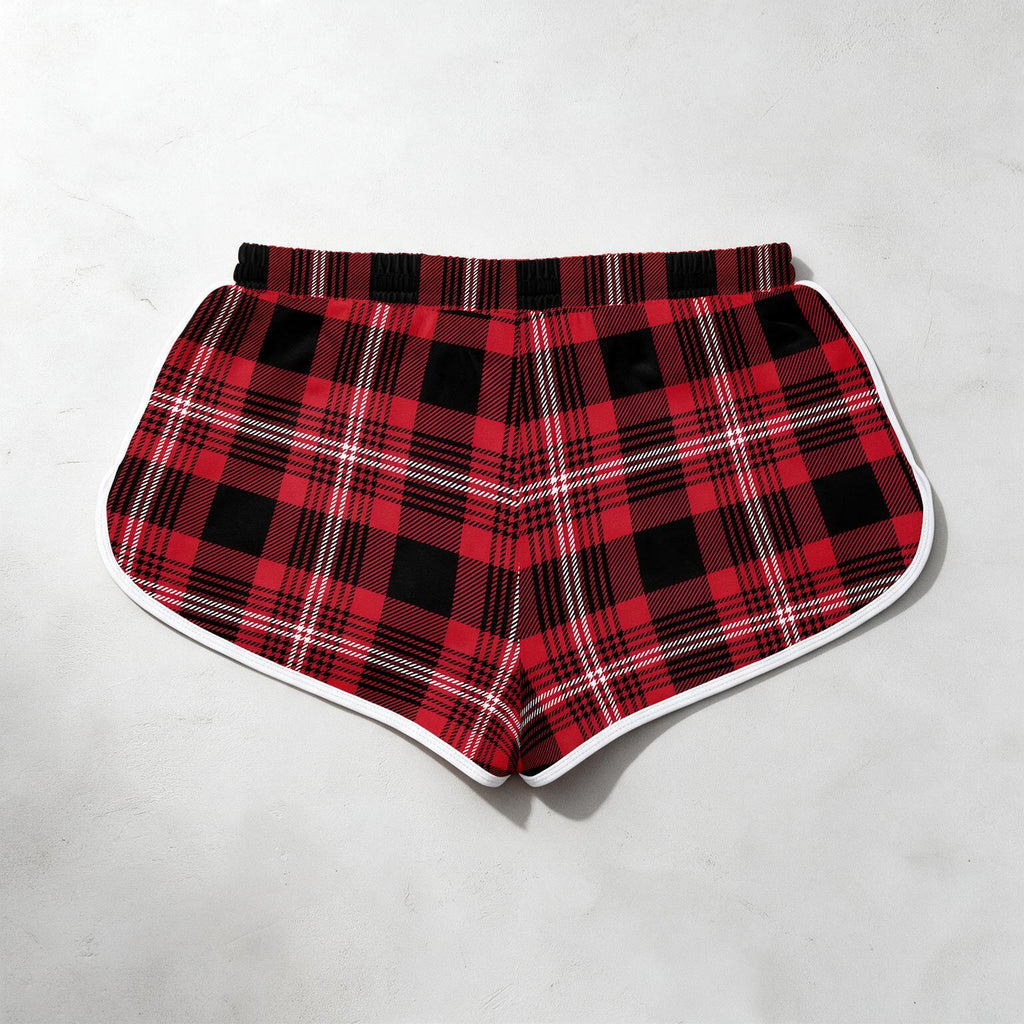 Red and black plaid shorts with a white border trim, laid flat on a light gray textured background.