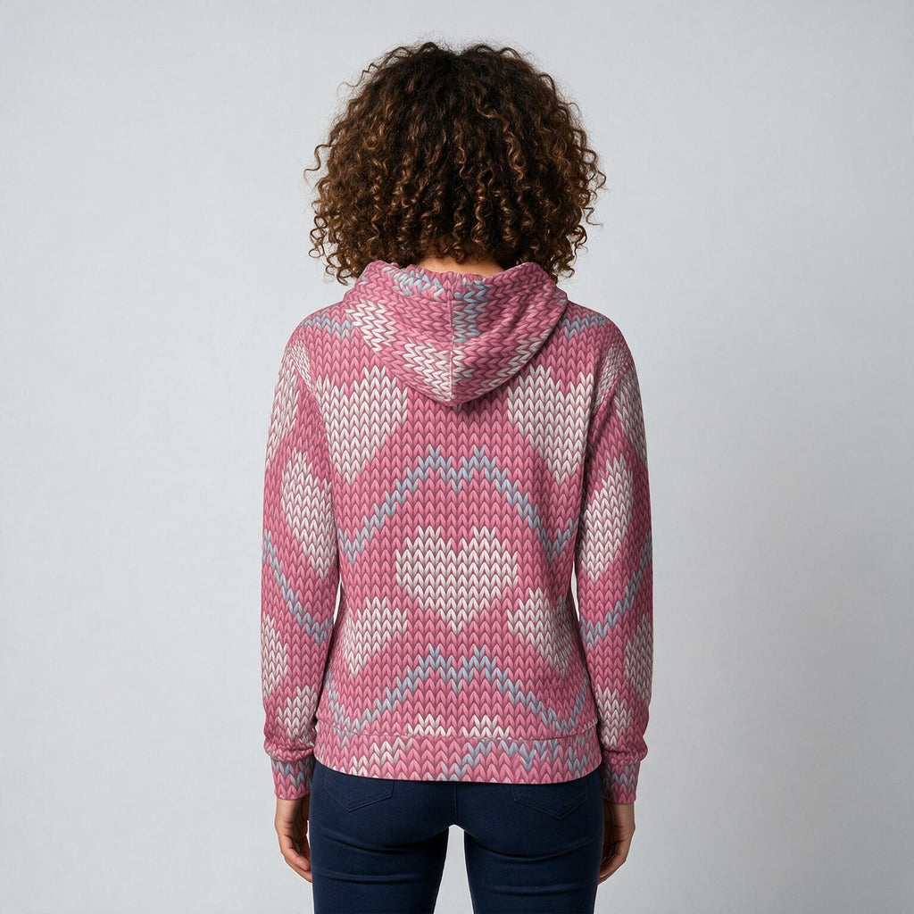 A person viewed from the back wearing a pink, white, and light blue patterned knit hoodie with dark blue jeans, set against a plain light gray background.