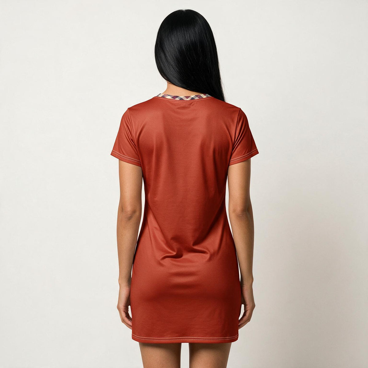A woman viewed from behind wearing a short-sleeve rust-orange t-shirt dress against a plain off-white background.