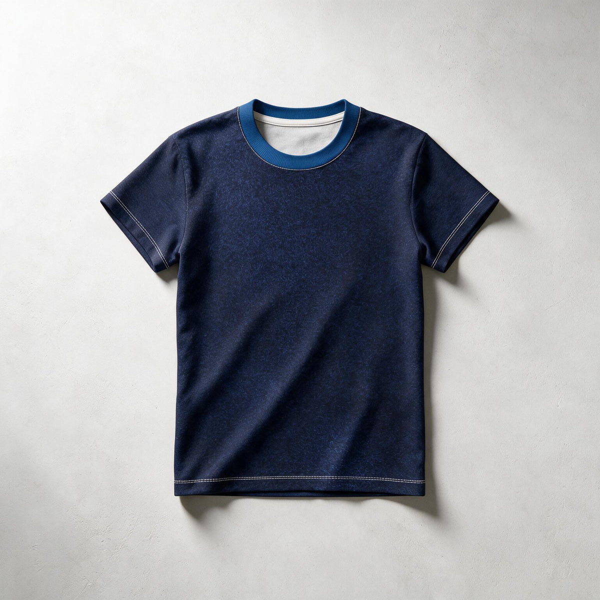 A dark navy blue short-sleeve t-shirt with a contrasting medium blue ribbed crew neck and white inner collar, laid flat on a light gray textured background.