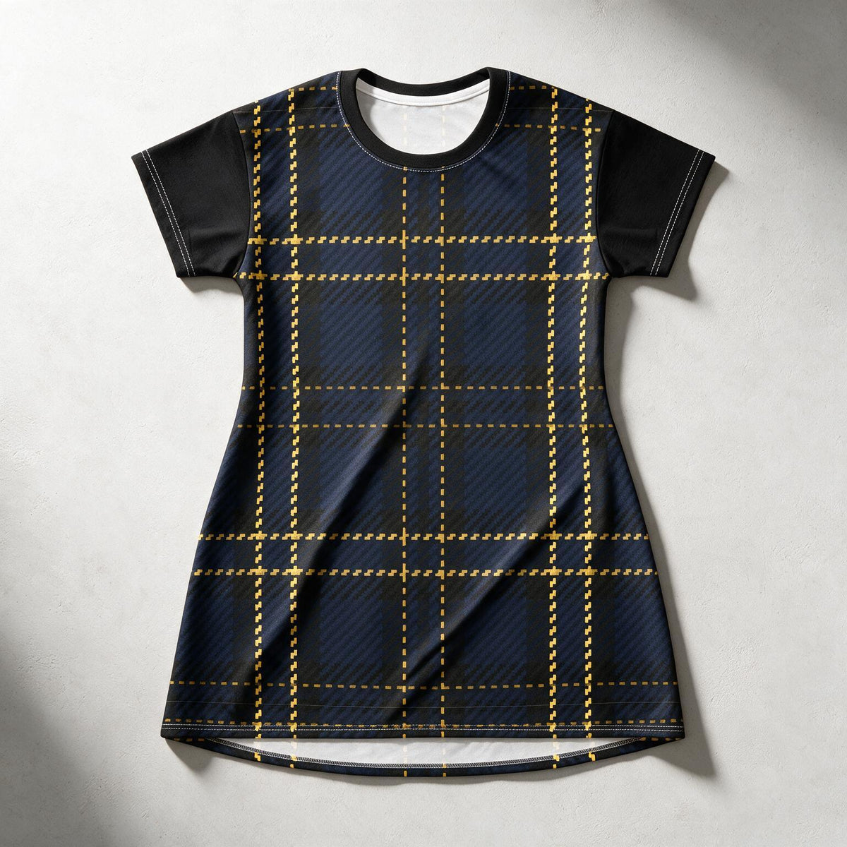 A short-sleeve crewneck t-shirt dress featuring a dark navy blue and black tartan plaid pattern with gold dashed grid lines, laid flat on a light gray textured background.