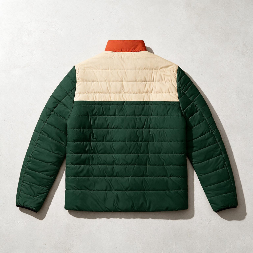 A color-blocked quilted puffer jacket shown from the back, featuring a dark green body, a cream-colored upper back panel, and a rust-orange collar, laid flat on a light gray textured background.