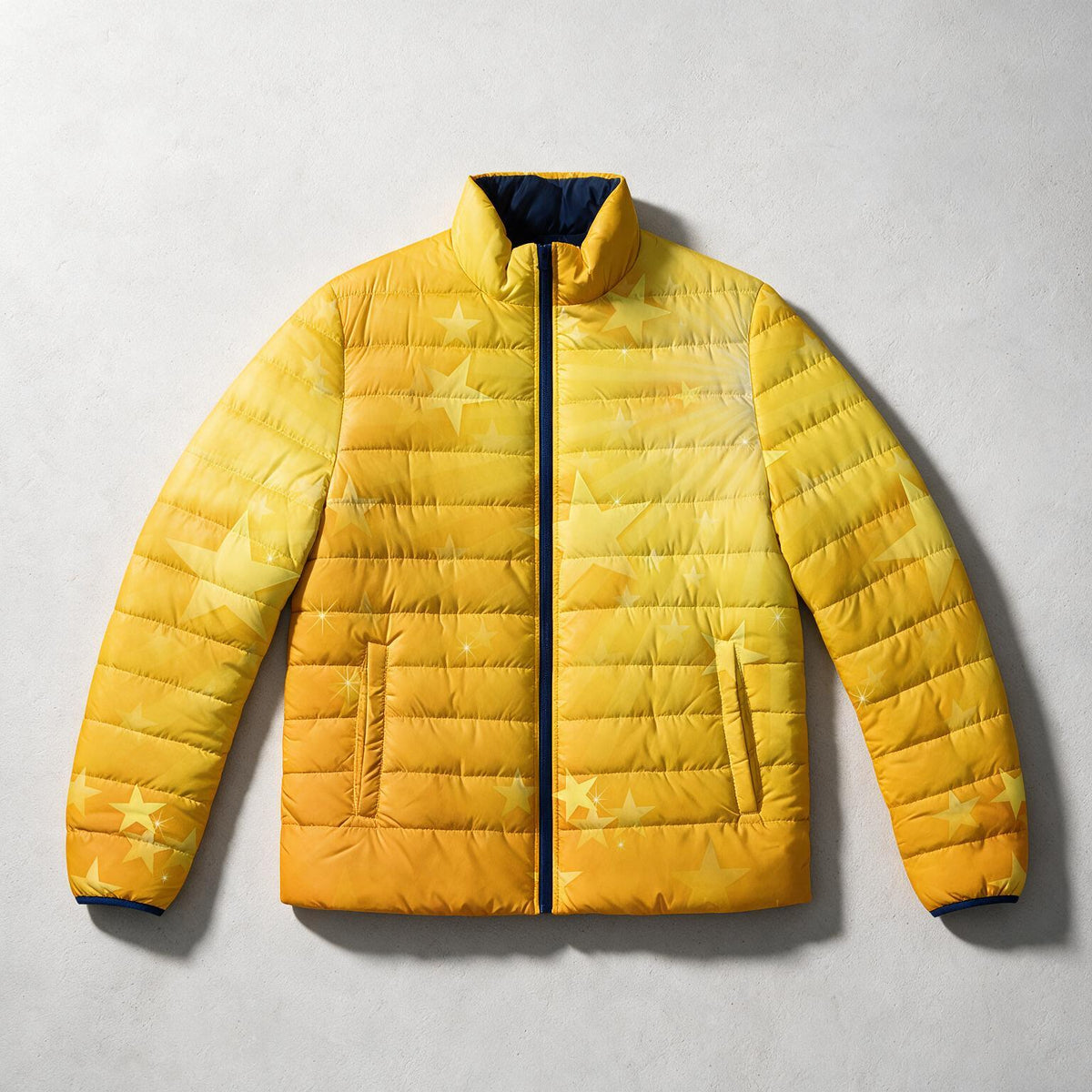 A yellow quilted puffer jacket with a subtle star pattern, laid flat on a light gray textured background.