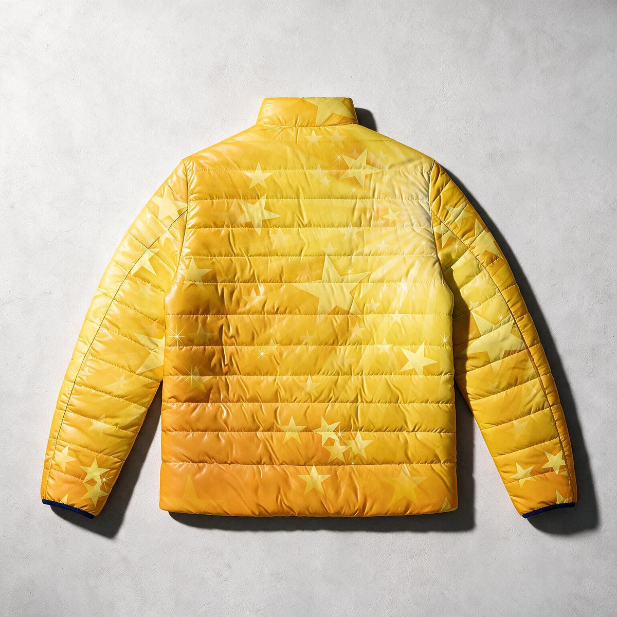 A yellow quilted puffer jacket with an allover star pattern, shown from the back on a textured gray background.
