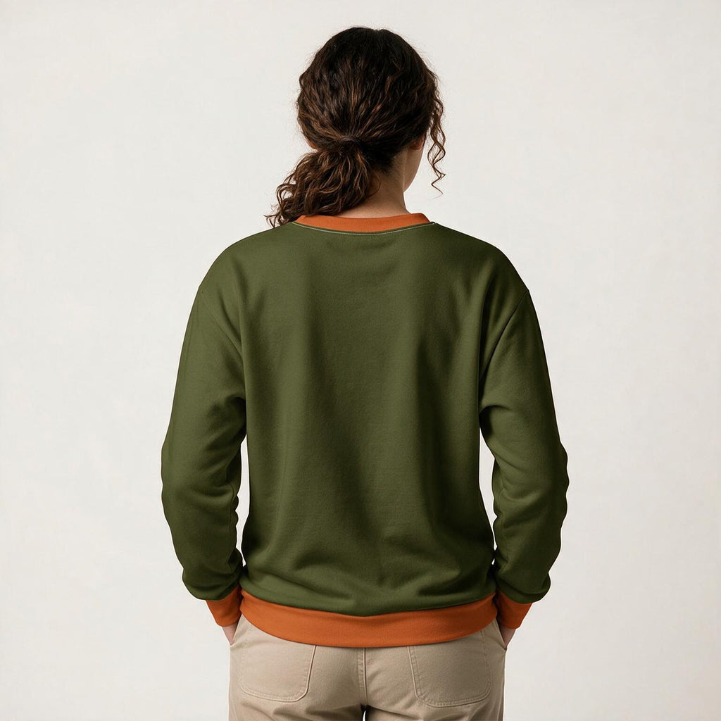A woman viewed from behind wearing an olive green crewneck sweatshirt with contrasting orange ribbed trim at the collar, cuffs, and hem, paired with beige pants against a plain off-white background.