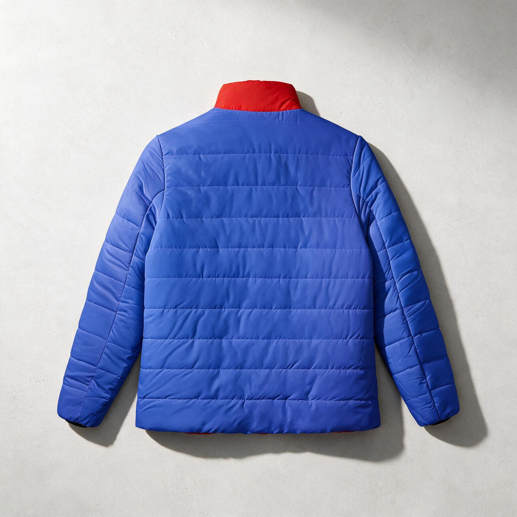 A bright blue quilted puffer jacket shown from the back, featuring a contrasting red collar, laid flat against a textured light gray background.