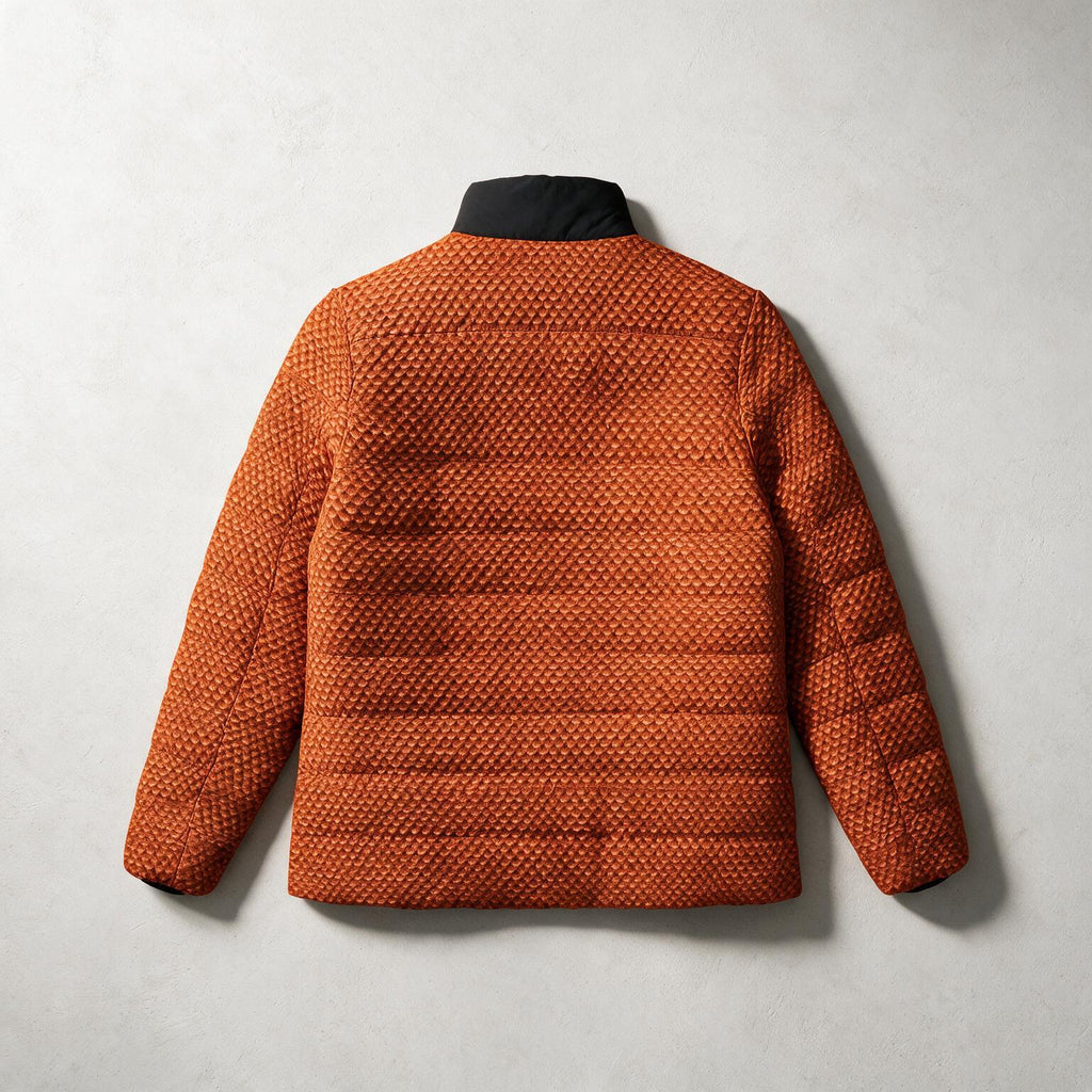 An orange quilted puffer jacket with a textured geometric pattern, shown from the back against a light gray textured background.