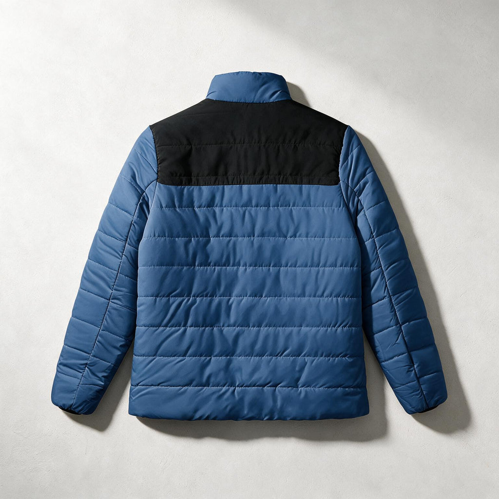 A blue and black quilted puffer jacket shown from the back, laid flat against a light gray textured background.