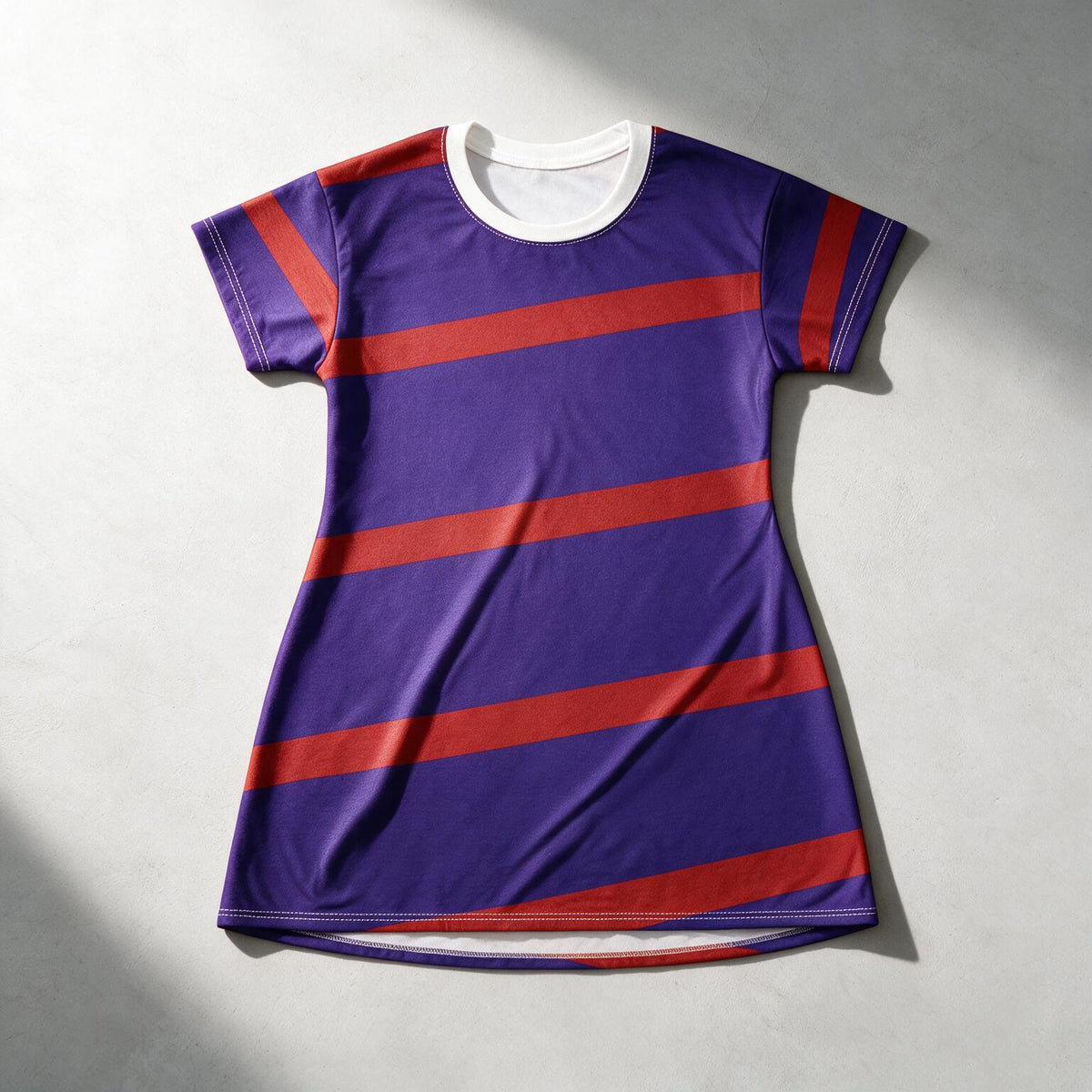 A short-sleeve athletic t-shirt dress in purple with diagonal red stripes and a white crew neck, laid flat on a light gray textured background.