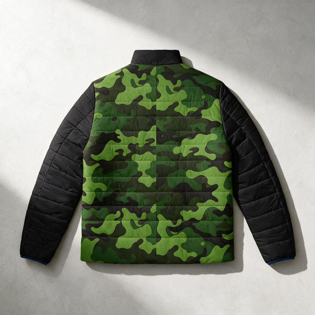 A quilted puffer jacket shown from the back, featuring a green camouflage pattern across the back panel and solid black quilted sleeves, photographed flat against a textured light gray background with diagonal shadows.