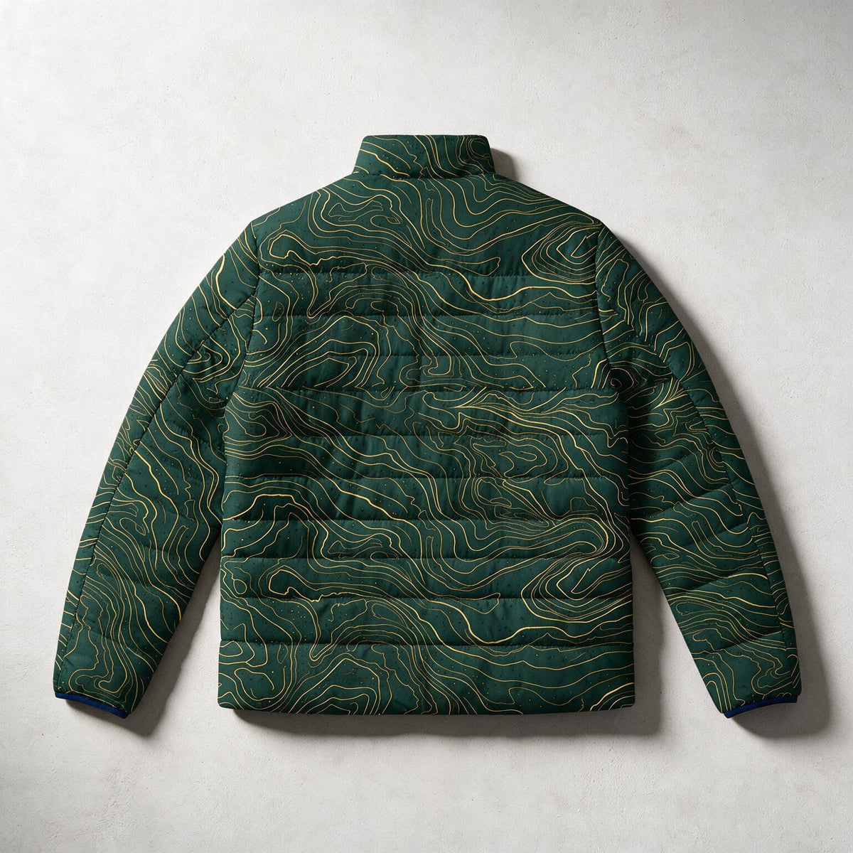 A dark green quilted puffer jacket with a topographic contour line pattern in gold, shown from the back against a light gray textured background.