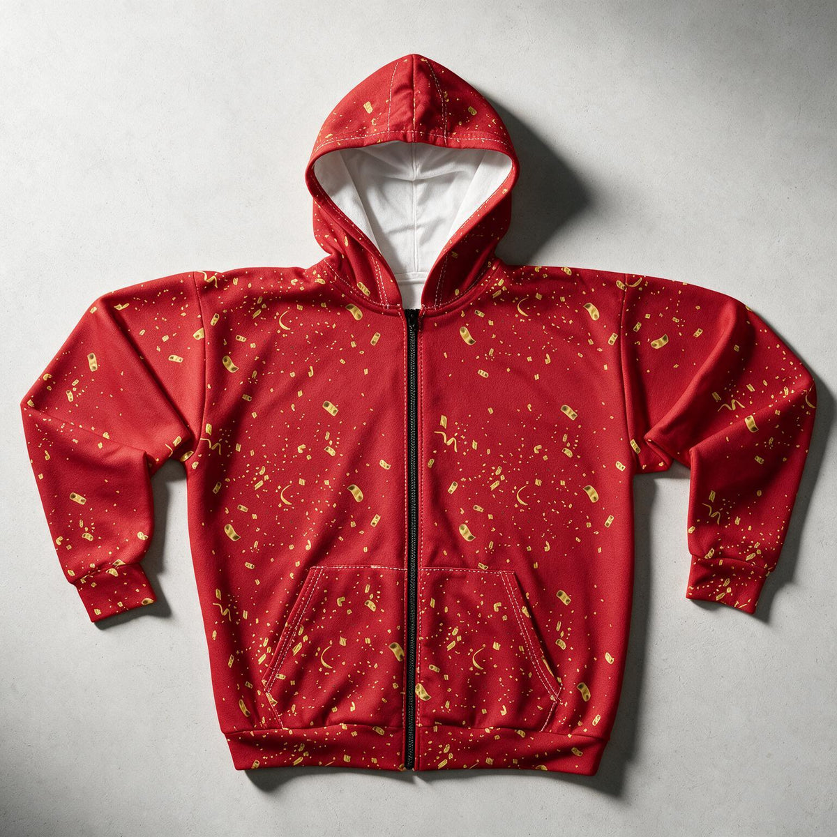 A red zip-up hoodie with a gold celestial print of stars, moons, and constellations, laid flat on a gray background. The hoodie features a white interior lining and a black zipper.