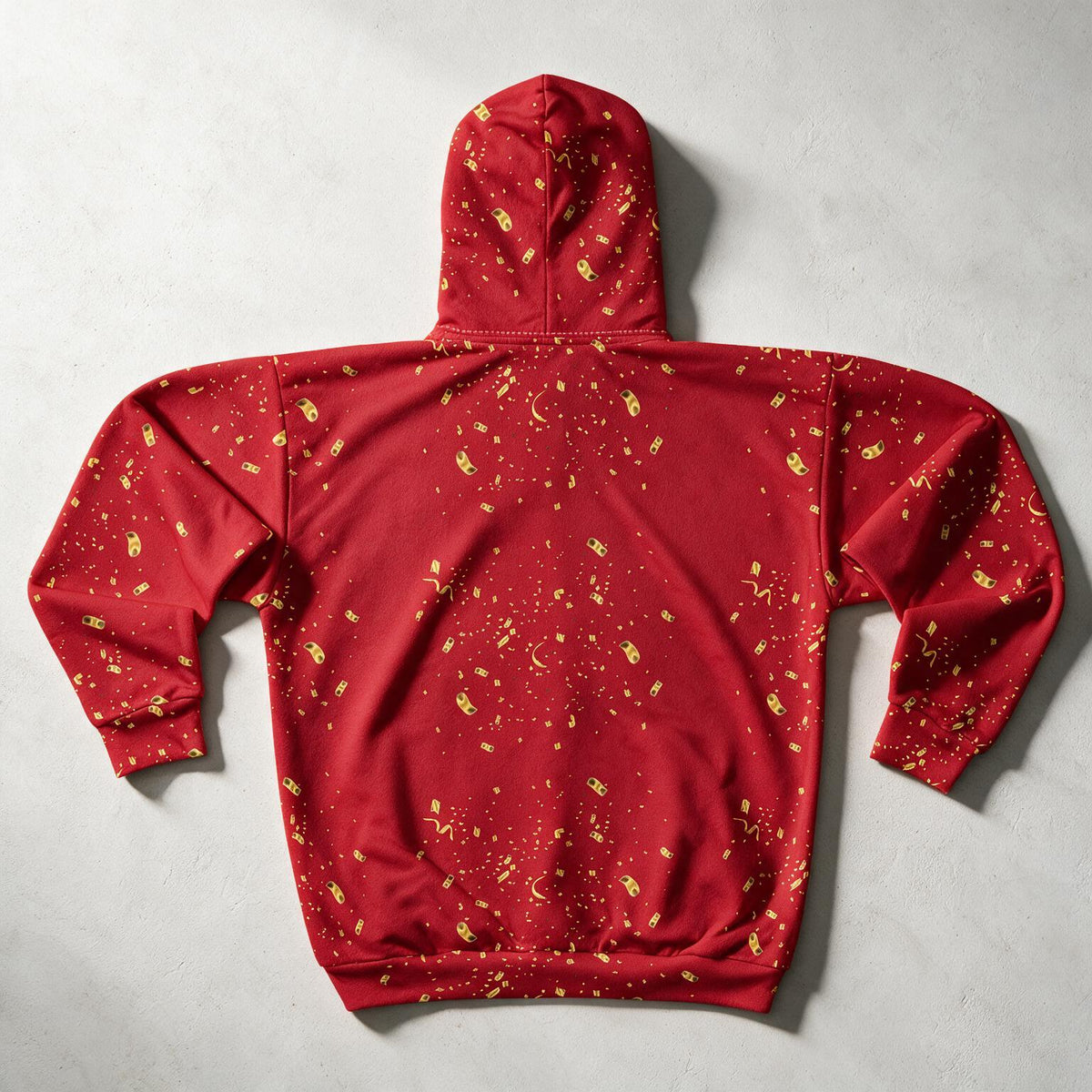 A red hooded sweatshirt with a gold celestial print of stars, moons, and constellations, laid flat on a textured gray background.