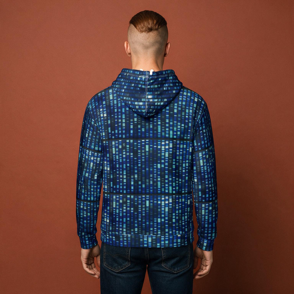 A man viewed from behind wearing a blue and teal digital matrix-style patterned hoodie and dark jeans, standing against a solid terracotta brown background.