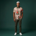 Man wearing a floral shirt and dark pants on a green background