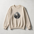 A beige crewneck sweatshirt featuring a graphic print of a silver disco ball in the center, laid flat on a light gray textured background.